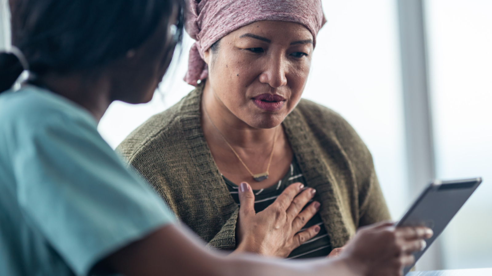 post-chemo older Asian woman discussing options with black female nurse