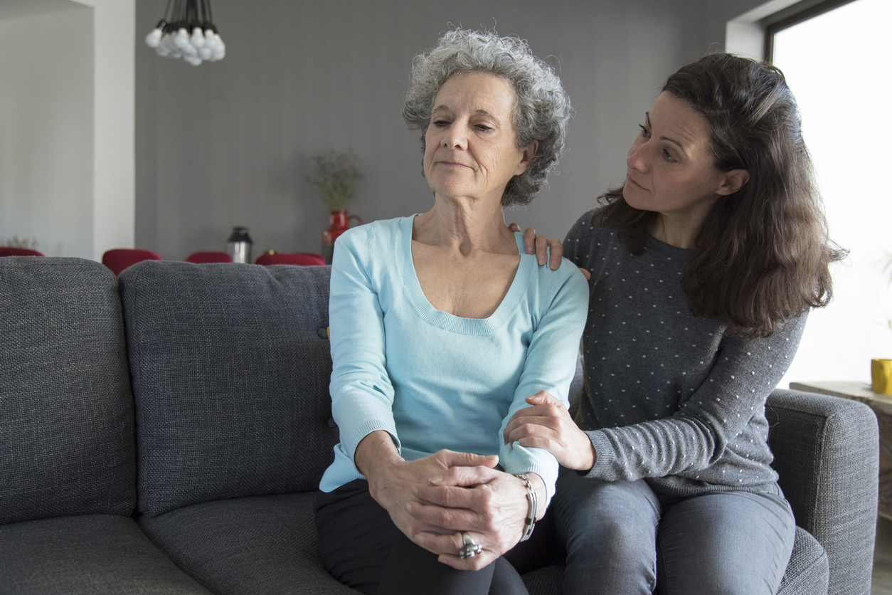Younger woman consoling older woman on couch