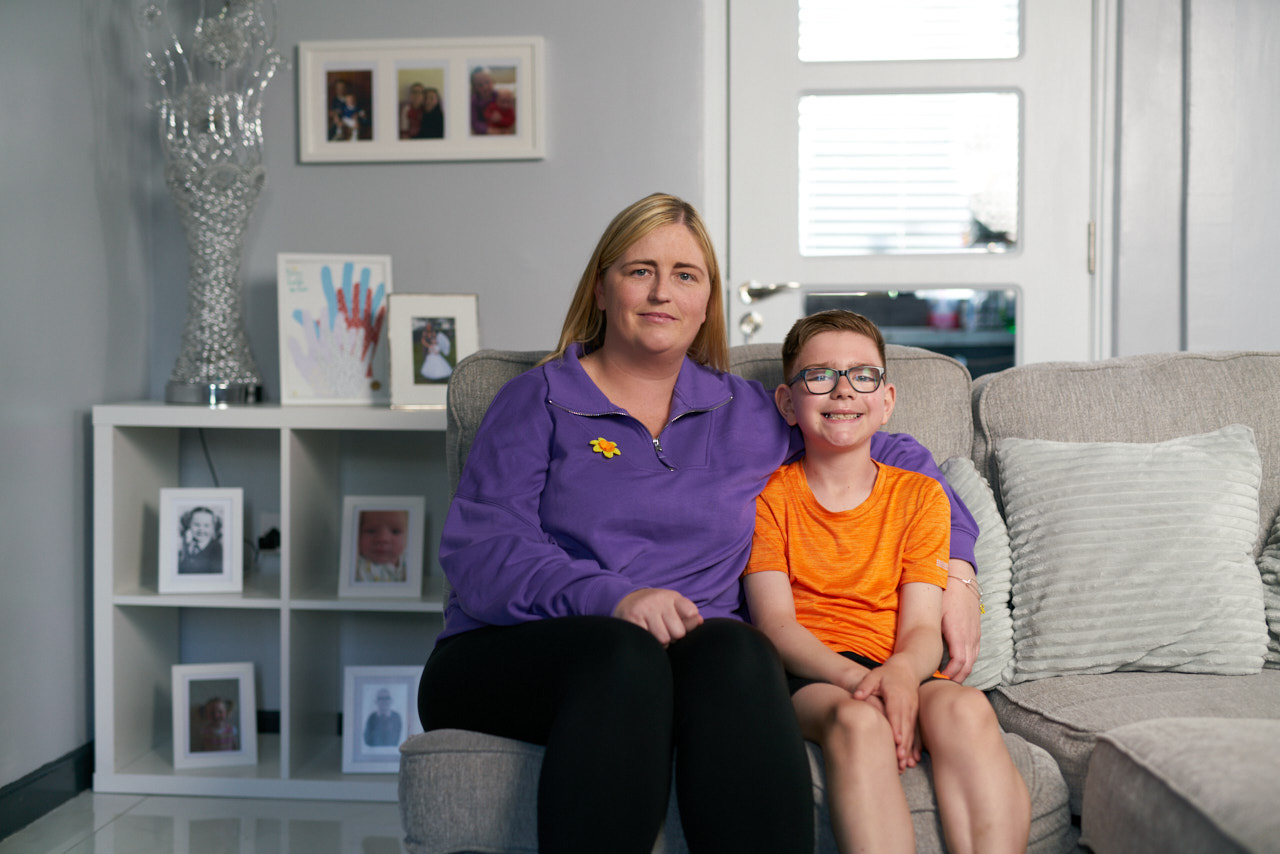 Caiden and his Mam sitting on their sofa