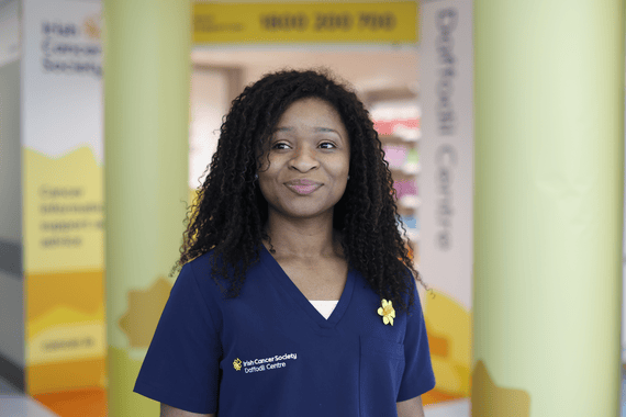 A Daffodil Centre nurse smiles to camera wearing a navy uniform 