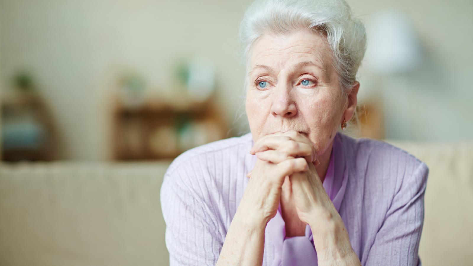 Older woman looking concerned with her hands clasped under her chin