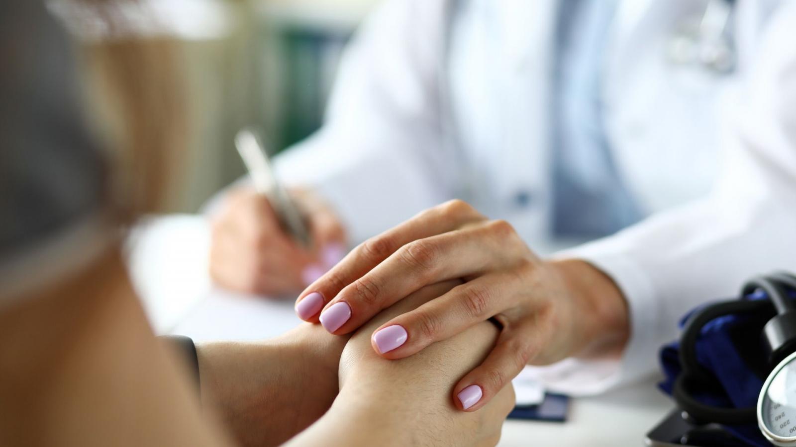 One person's hand over the other person's hand in a gesture of comfort