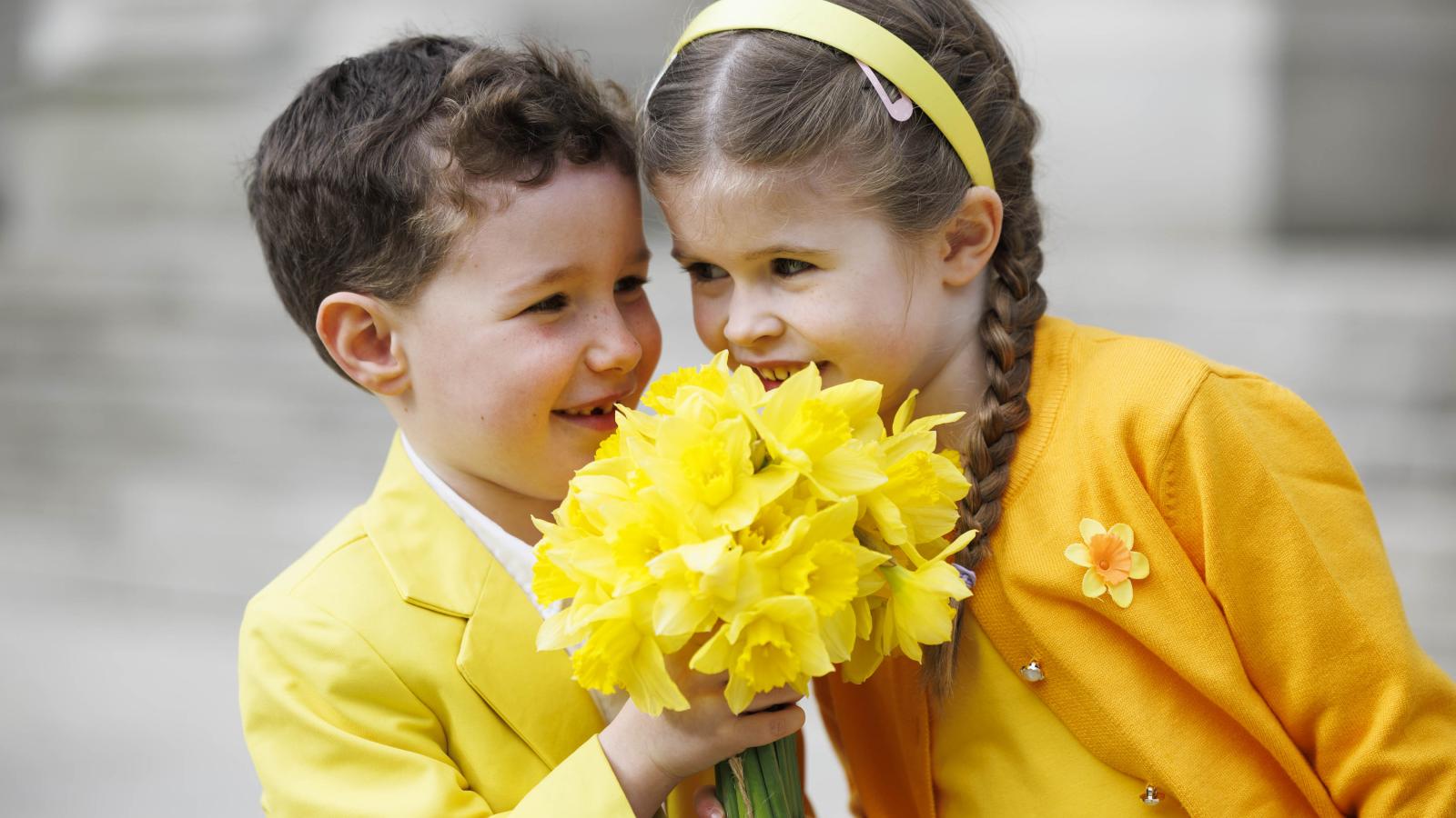 Kids dressed in yellow holding daffodils