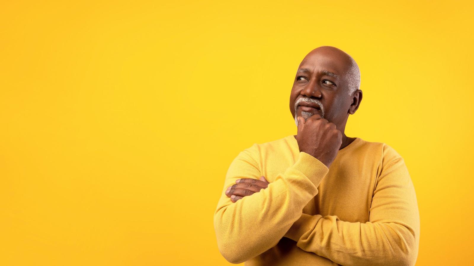 thinking middle-aged Black man on yellow background